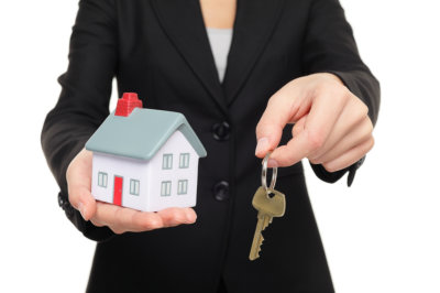 woman holding toy house and a key